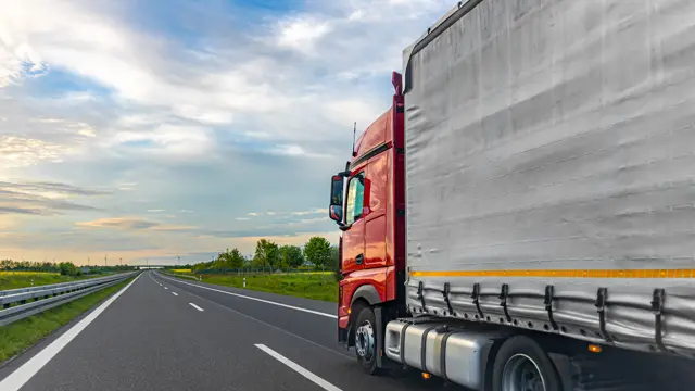 Red truck with a curtain-side trailer on an open highway