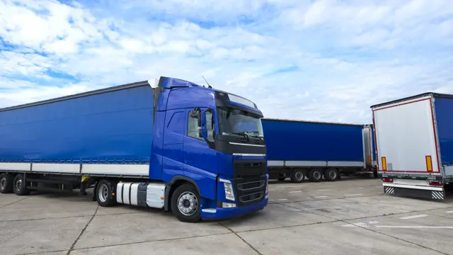 Blue heavy truck and trailers parked at a truck yard