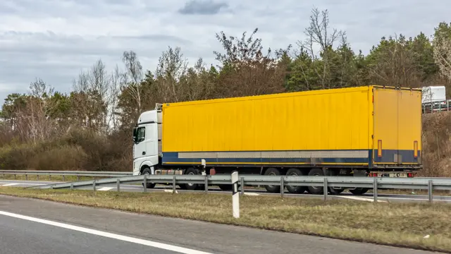 Truck with a yellow container trailer on a rural highway