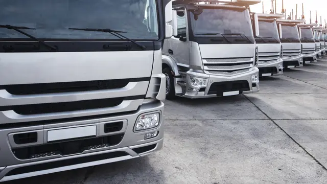 Row of white delivery trucks parked in a fleet yard