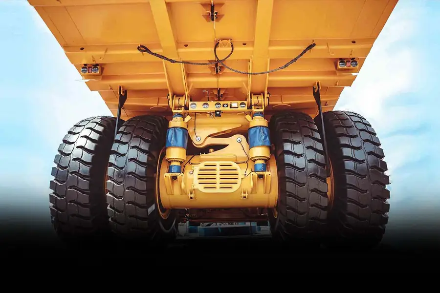Yellow mining dump truck seen from below with large OTR tyres