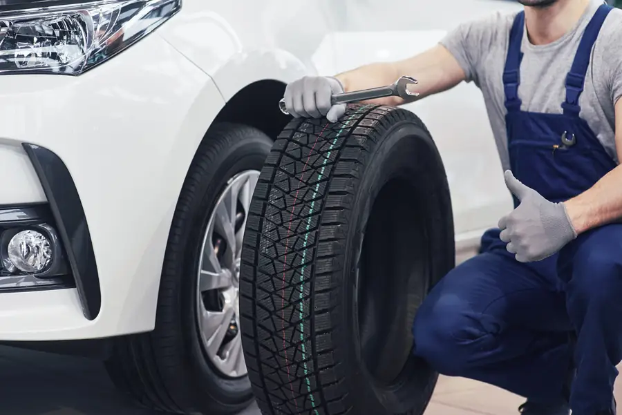 Tyre technician holding a new car tyre and giving a thumbs up